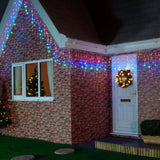Instalație Crăciun franjuri montată la streașină casă, efect lumini multicolor în exterior, noapte